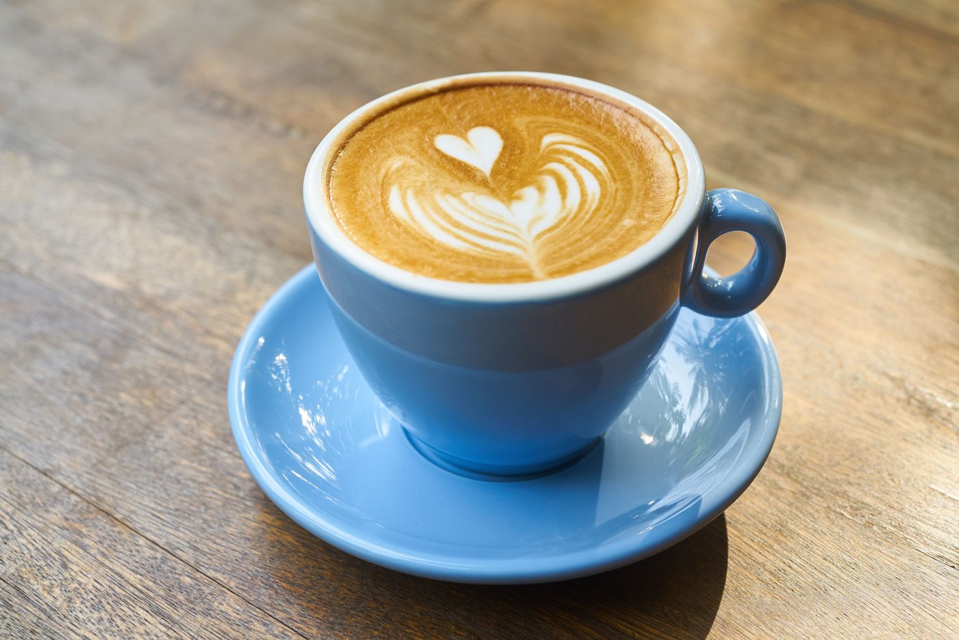 A latte with heart latte art in a blue cup